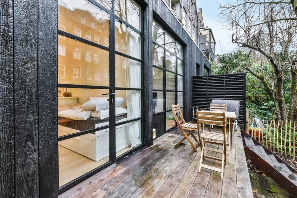 Balcony with wooden deck and outdoor furniture in front of a modern black building exterior.
